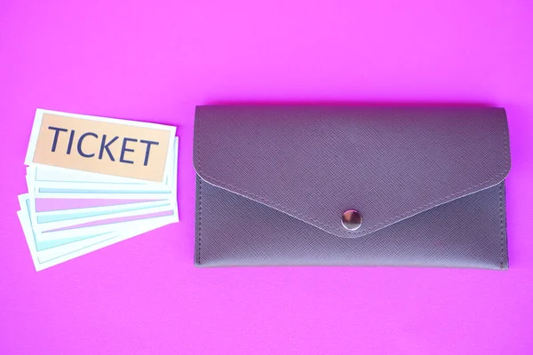 Leather envelope and pile of paper tickets. Pink background. Concept, tickets for passing or enter to join activity or public vehicles. Tickets for playing games. Teaching aids.