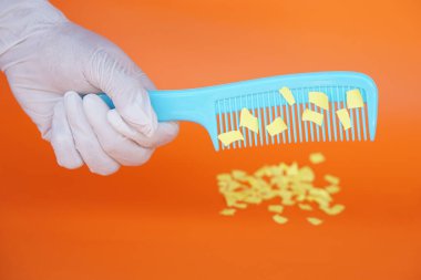 Tarak ve küçük kağıt parçaları. Ekipman, statik elektrik deneyi için hazır. Turuncu arka plan. Konsept, fen dersi, eğlenceli ve kolay bir deney. Eğitim. Öğretmenlik yardımları. 