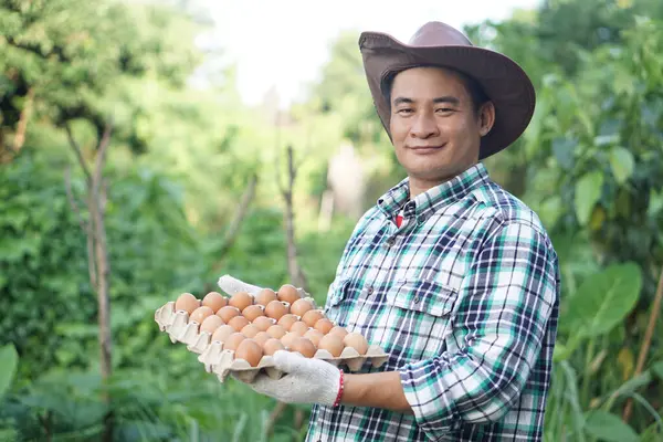 Handsome Asian man farmer holds tray of eggs at garden. Concept, Organic agricultural farming, Farmers produce healthy eco food. Best food during bad economy. Delivery to home.