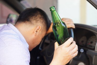 Sarhoş adam arabada bira şişesi tutuyor. Konsept, araba kullanmama kampanyası, araba kazası ve yasa dışı yollara yol açabilecek alkolü içme. Sarhoşken tehlikeli araba kullanmak.  