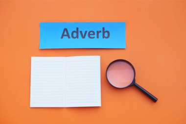 Kağıt kelime kartı, yazılı adres, büyüteç ve kağıt defter. Turuncu arka plan. Konsept, İngilizce dil bilgisi. İngilizce dersi öğreniyorum..   