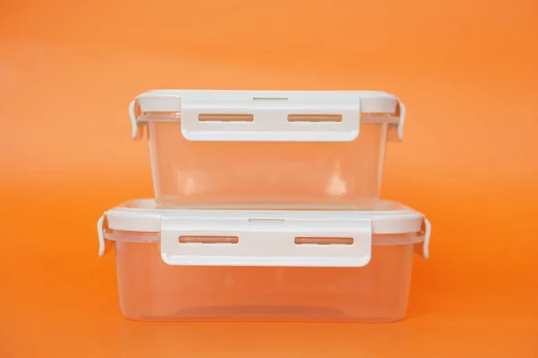 Empty transparent boxes, containers. Orange background. Concept, kitchenware use for contains food as lunch box or keep fresh of food in refrigerator. Cleanable, reusable.