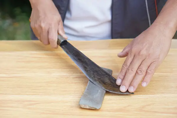 Closeup man hands sharpen knife on whetstone sharpener or grindstone. Concept, maintenance tools for cooking, make knife sharp ,not dull for long live using. Original style.