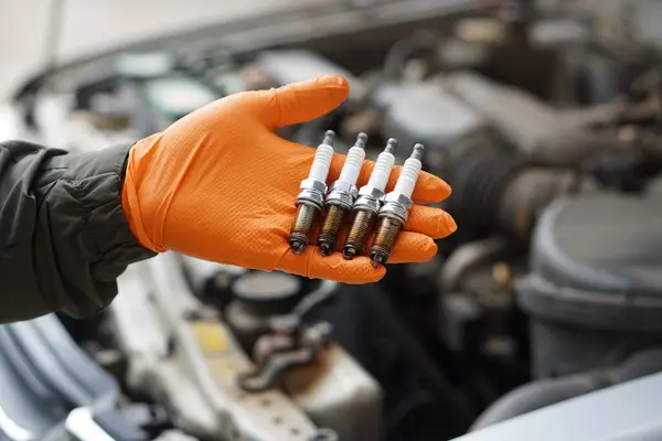 Tamirci elini kapat, eski bujiyi tut, yedek motor parçası. Konsept, makine bakımı, tamir, onarım, kontrol veya motor uzmanları tarafından otomobil sorunları teşhis.                          
