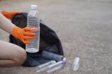 Yakından eldiven tak, plastik şişe tut. Konsept, çöp yönetimi, yeniden kullanılmış, geri dönüştürülmüş plastik şişeler. En iyi çevre için temiz ve kamu hizmeti yapın. Sıfır atık.     
