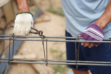 Kapalı inşaat işçisi beton işçiliğinin metal çubuk takviyesine demir tel bağlıyor. Konsept, inşaat işi temel yapısı. İnşaatçı mesleği.    
