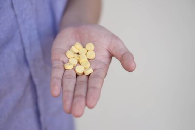 Ellerindeki sarı ağrı kesici ilaçlara odaklan. Kavram, sağlık, tedavi, çare hastalığı ve evde kendi kendine terapi. Aşırı doz hapları alıyor..   