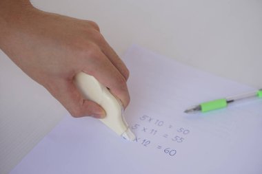 Hand use correction tape to erase incorrect numbers on paper. Concept, educational equipment, stationary item to delete or erase mistake in writing. Easy and convenient to use.           clipart