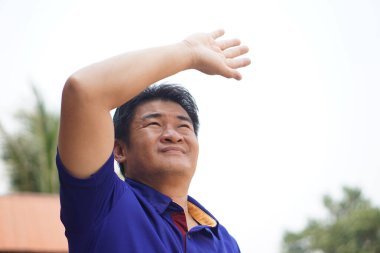 Asyalı adam dışarıda, yüzü gökyüzüne dönük, başını uzatmış, sıcak ve kötü hissediyor. Kavram, sıcak havada dışarıda durmak sıcak çarpması semptomu oluşturabilir. Küresel sıcaklık.                     