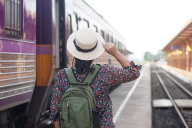 Kadın yolcuların arka planı, beyaz şapka ve sırt çantası takmak, Tayland 'daki yerel tren istasyonunda trenle seyahat etmek. Kavram, yaşam tarzı. Seyahat, seyahat turizmi.         