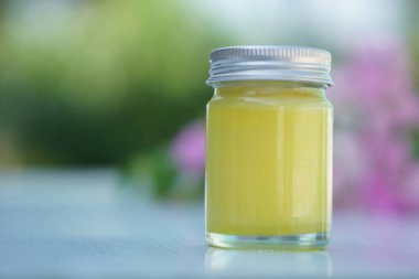 Bir şişe ev yapımı Tayland bitkisi sarısı merhemi. Çiçekle süslenmiş. Kavram, Tayland yerel bilgeliği parfümlü şifalı bitkiler kullanarak sprey ve masaj merhemi yapmak..               