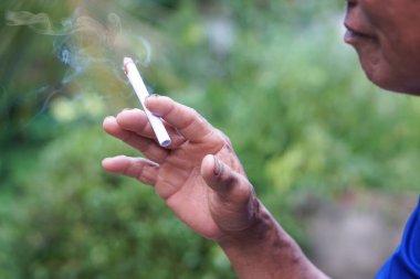 Sağlıksız elleri sigara içmek için ev yapımı sigara tutuyor. Sigara içmek sağlığa zararlıdır. Rahatlamak için özel favori ama sağlık sorunları ve kötü kokuya neden olabilir..     