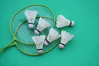 Shuttlecock ve raketler. Badminton spor malzemeleri yeşil arka planda. Konsept, spor, egzersiz, iyi sağlık için eğlence aktivitesi. Tüm cinsiyetler için popüler bir spor                          
