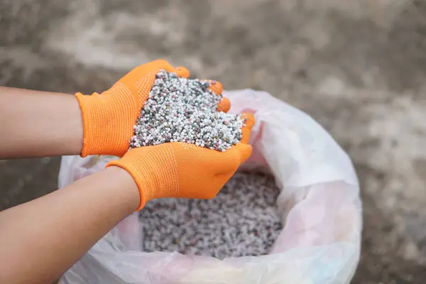 Kapalı ellerde karışık kimyasal gübre bulunur. Konsept; tarımda kimyasal gübre kullanımı azot (AND), fosfat (P2O5) ve potasyum (K2O) gibi temel besinlerden oluşur.).   