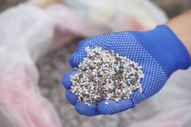 Kapalı ellerde karışık kimyasal gübre bulunur. Konsept; tarımda kimyasal gübre kullanımı azot (N), fosfat (P2O5) ve potasyum (K2O) gibi temel besinlerden oluşur.).    