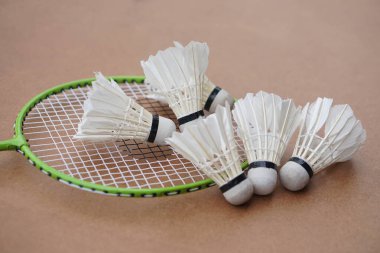 Mekik horozları ve raketler. Kahverengi arka planda Badminton spor malzemeleri. Konsept, spor, egzersiz, iyi sağlık için eğlence aktivitesi. Tüm cinsiyetler için popüler bir spor                     