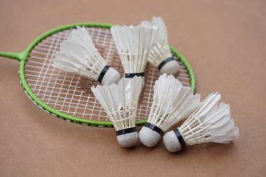Mekik horozları ve raketler. Kahverengi arka planda Badminton spor malzemeleri. Konsept, spor, egzersiz, iyi sağlık için eğlence aktivitesi. Tüm cinsiyetler için popüler bir spor                          