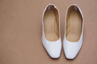 Kahverengi arka planda beyaz ayakkabılar. Ofis çalışanları için kavram, moda, resmi ve kibar ayakkabılar ya da hemşireler için ofiste ya da hastanede beyaz üniformayla uyumlu ayakkabılar giymek. Ayakkabılar.        