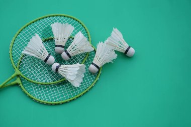 Shuttlecock ve raketler. Badminton spor malzemeleri yeşil arka planda. Konsept, spor, egzersiz, iyi sağlık için eğlence aktivitesi. Tüm cinsiyetler için popüler bir spor                