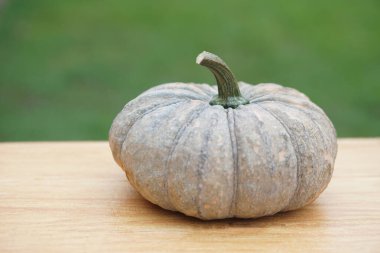 Ahşap masada organik balkabağı meyvesi ve yeşil arka plan. Kavram. Tarım mahsulü. Yemek malzemesi, çeşitli menüler için pişirilebilir. Sağlıklı yemek..     