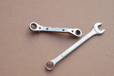 Kahverengi arka planda metal krom anahtarlar ya da yayıcılar. Kavram, tamirci, mekanik aletler. Tamir ve onarım için ekipman, günlük yaşamda yenileme.    