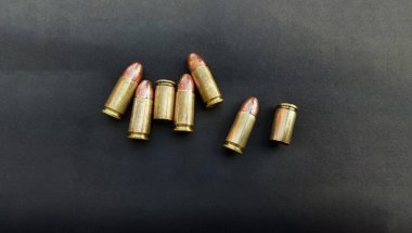 9mm 'lik tabanca mermileri ve mermi kovanları. Düz yatıyordu. Mesaj için yer var. Kavram, ateş etmek için tehlikeli bir silah..    