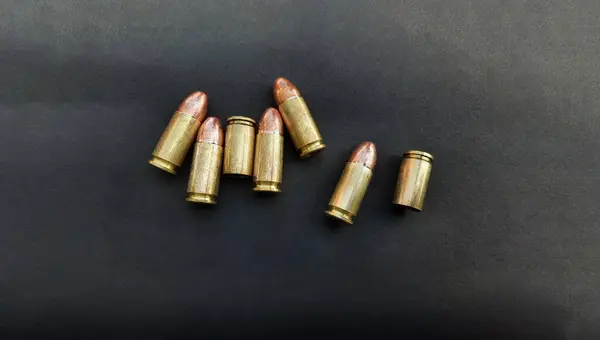 9mm 'lik tabanca mermileri ve mermi kovanları. Düz yatıyordu. Mesaj için yer var. Kavram, ateş etmek için tehlikeli bir silah..    