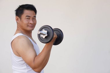 Asyalı adam egzersiz için dambıl kaldırıyor. Konsept, vücut geliştirme egzersizi. Kaslarını güçlendir. Ağırlık kaldırma. Sağlıklı bir yaşam tarzı. Vücut çalış, güçlü ol..               