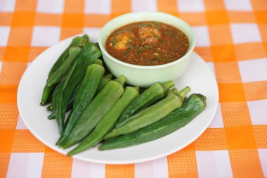 Kaynamış yeşil bamya ya da bayanın parmak meyvesi ve biber ezmesi. Sağlıklı yemek kavramı. Lezzetli bir menü ve yerel organik meyve ve sebzelerden elde edilen şifalı bitkilerle sağlık için iyi..   