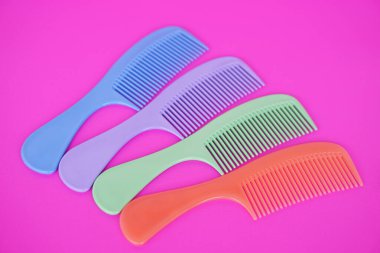Pembe arka planda izole edilmiş saplı renkli plastik saç tarakları. Konsept: saç güzelliği veya dekorasyonu için ekipman veya araç.                   