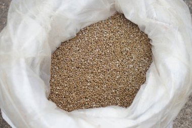 Plastik bir çuvaldaki granüler gübre. Toprağı zenginleştirmek ve bitkilerin büyümesini hızlandırmak için kullanılır. Sürdürülebilir tarımı desteklemek ve mahsul verimini ve toprak sağlığını iyileştirmek için temel besinlerle dolu.                               