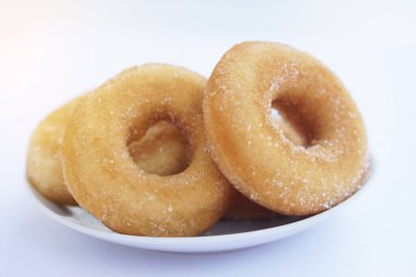 Beyaz tabakta ev yapımı şekerli süt çörekleri, yumuşak ve kabarık dokular, tereyağlı aroma, yağsız kızartma. Yemek ve satış için lezzetli bir ikramdı. Kızarmış hamur işi ve tatlı tatlı konsepti..