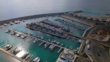 Ayia Napa Kıbrıs. Ayia Napa Marina 'nın kuş bakışı manzarası. Güneşli bir günde yüksek binalar ve marina. Akdeniz ve modern mimari. Denizin arka planına karşı doğa ve şehircilik.