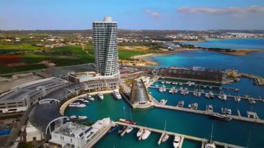 Ayia Napa Kıbrıs. Ayia Napa Marina 'nın kuş bakışı manzarası. Güneşli bir günde yüksek binalar ve marina. Akdeniz ve modern mimari. Denizin arka planına karşı doğa ve şehircilik.