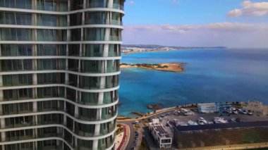 Ayia Napa Kıbrıs. Ayia Napa Marina 'nın kuş bakışı manzarası. Güneşli bir günde yüksek binalar ve marina. Akdeniz ve modern mimari. Denizin arka planına karşı doğa ve şehircilik.