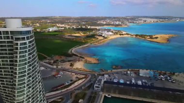 Ayia Napa Kıbrıs. Ayia Napa Marina 'nın kuş bakışı manzarası. Güneşli bir günde yüksek binalar ve marina. Akdeniz ve modern mimari. Denizin arka planına karşı doğa ve şehircilik.