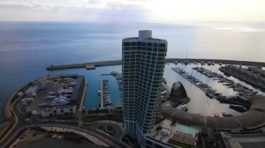 Ayia Napa Kıbrıs. Ayia Napa Marina 'nın kuş bakışı manzarası. Güneşli bir günde yüksek binalar ve marina. Akdeniz ve modern mimari. Denizin arka planına karşı doğa ve şehircilik.