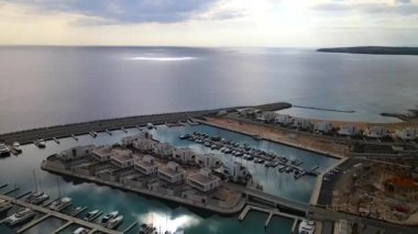 Ayia Napa Kıbrıs. Ayia Napa Marina 'nın kuş bakışı manzarası. Güneşli bir günde yüksek binalar ve marina. Akdeniz ve modern mimari. Denizin arka planına karşı doğa ve şehircilik.