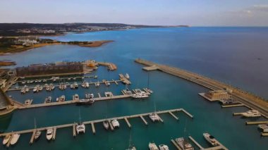 Ayia Napa Kıbrıs. Ayia Napa Marina 'nın kuş bakışı manzarası. Güneşli bir günde yüksek binalar ve marina. Akdeniz ve modern mimari. Denizin arka planına karşı doğa ve şehircilik.
