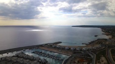 Ayia Napa Kıbrıs. Ayia Napa Marina 'nın kuş bakışı manzarası. Güneşli bir günde yüksek binalar ve marina. Akdeniz ve modern mimari. Denizin arka planına karşı doğa ve şehircilik.