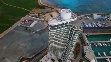 Ayia Napa Kıbrıs. Ayia Napa Marina 'nın kuş bakışı manzarası. Güneşli bir günde yüksek binalar ve marina. Akdeniz ve modern mimari. Denizin arka planına karşı doğa ve şehircilik.