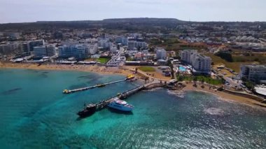 Protaras, Kıbrıs 'ta yaz günleri. Kamera turkuaz Akdeniz 'in ve otellerle çevrili sahil hattının üzerinden uçuyor..