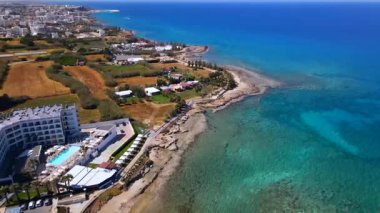 Protaras, Kıbrıs 'ta yaz günleri. Kamera turkuaz Akdeniz 'in ve otellerle çevrili sahil hattının üzerinden uçuyor..