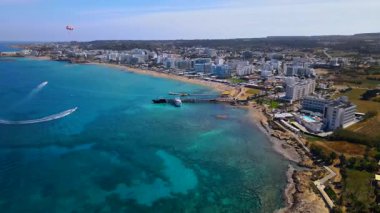 Protaras, Kıbrıs 'ta yaz günleri. Kamera turkuaz Akdeniz 'in ve otellerle çevrili sahil hattının üzerinden uçuyor..