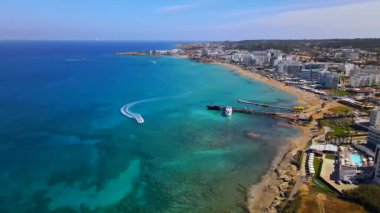 Protaras, Kıbrıs 'ta yaz günleri. Kamera turkuaz Akdeniz 'in ve otellerle çevrili sahil hattının üzerinden uçuyor..