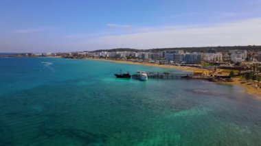 Protaras, Kıbrıs 'ta yaz günleri. Kamera turkuaz Akdeniz 'in ve otellerle çevrili sahil hattının üzerinden uçuyor..