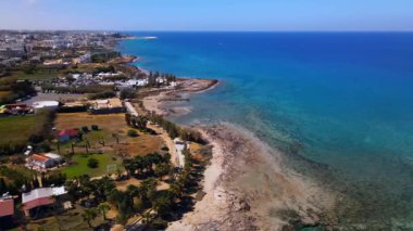 Protaras, Kıbrıs 'ta yaz günleri. Kamera turkuaz Akdeniz 'in ve otellerle çevrili sahil hattının üzerinden uçuyor..