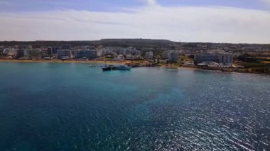 Protaras, Kıbrıs 'ta yaz günleri. Kamera turkuaz Akdeniz 'in ve otellerle çevrili sahil hattının üzerinden uçuyor..