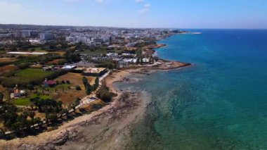 Protaras, Kıbrıs 'ta yaz günleri. Kamera turkuaz Akdeniz 'in ve otellerle çevrili sahil hattının üzerinden uçuyor..