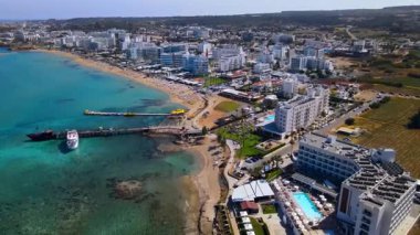 Protaras, Kıbrıs 'ta yaz günleri. Kamera turkuaz Akdeniz 'in ve otellerle çevrili sahil hattının üzerinden uçuyor..